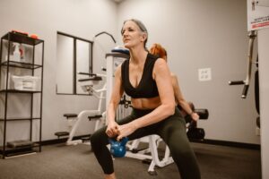 Woman over 40 doing kettlebell squats during a strength training session at the gym